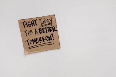 Cardboard sign with motivational quote: 'Fight today for a better tomorrow!' on white background.